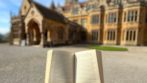 A person holiday a book open in front of Tyntesfield House.